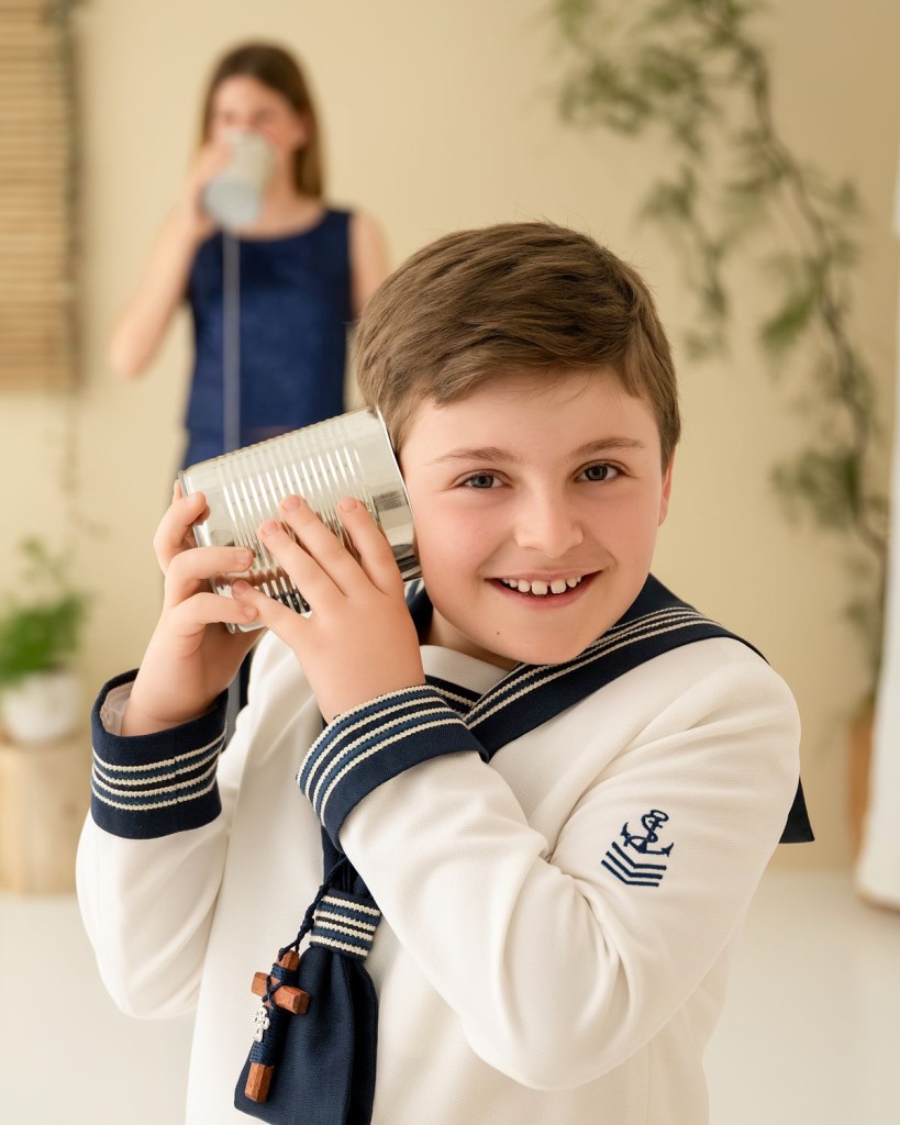 Fotógrafa de comuniones en Gijón: niño de marinero jugando al teléfono de latas con su hermana