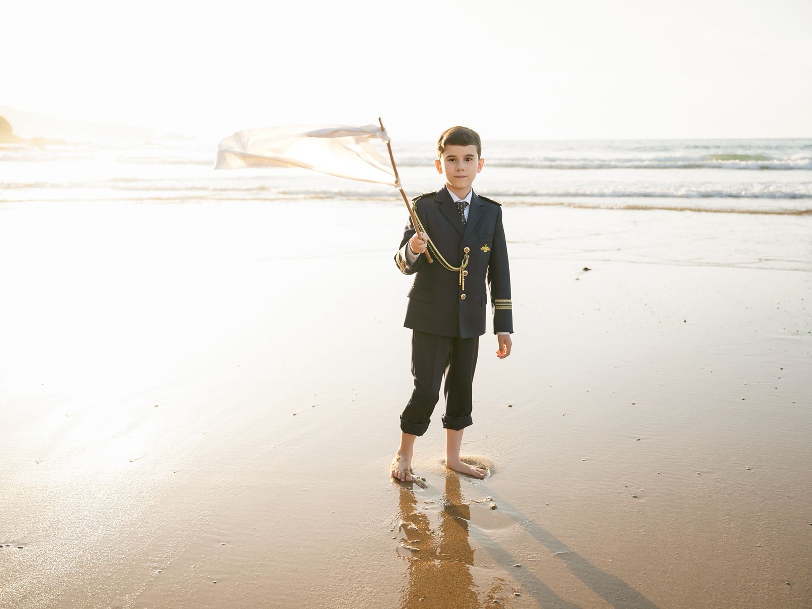 Cuándo contratar las fotografías de comunión en exteriores: niño con traje de almirante en una playa de Asturias